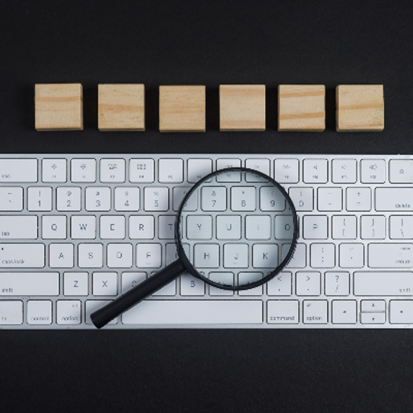 Keyboard, magnifier, wooden cubes on black desk background